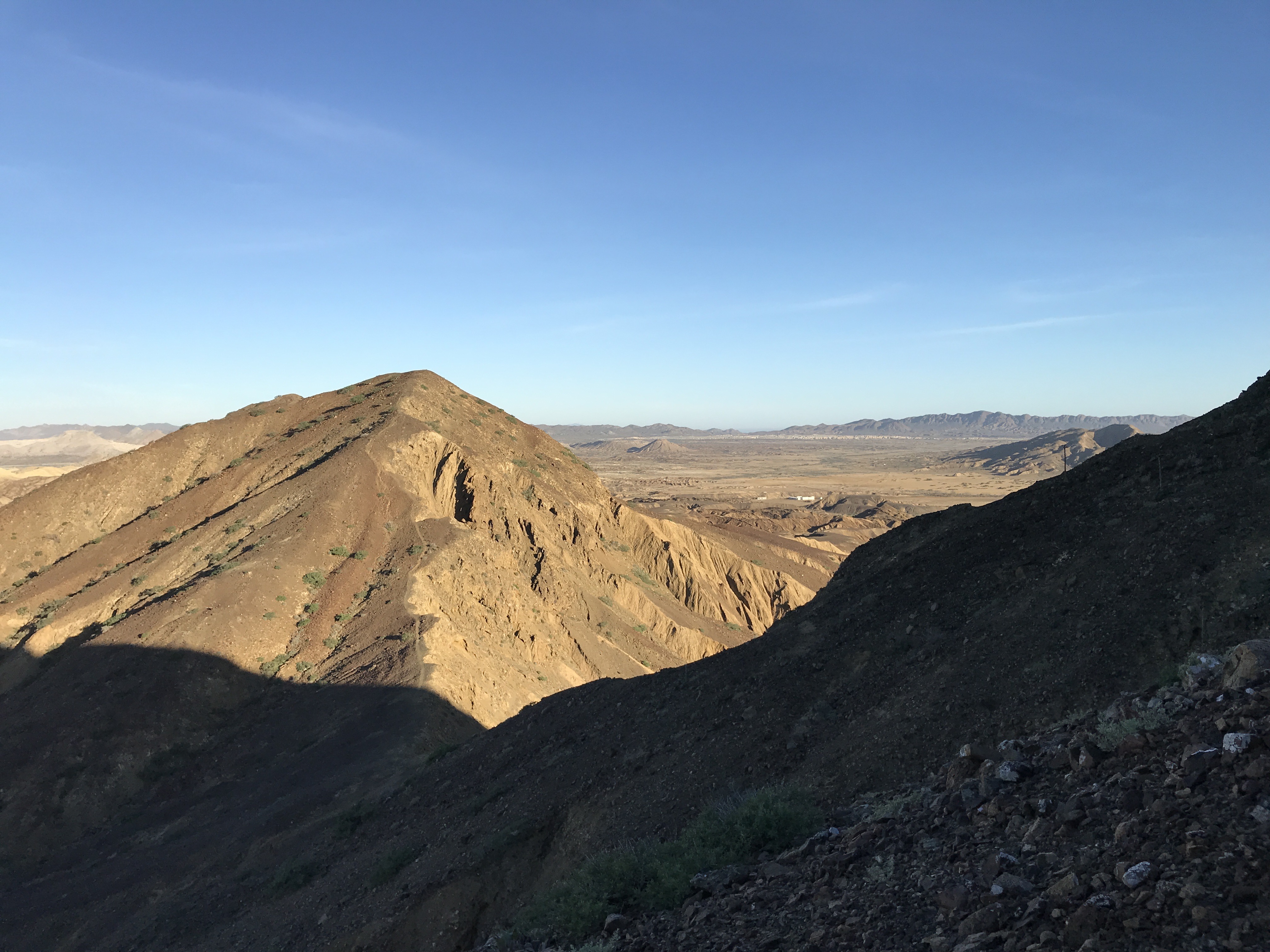 desert peak in foreground with expansive desert vista in background, blue sky